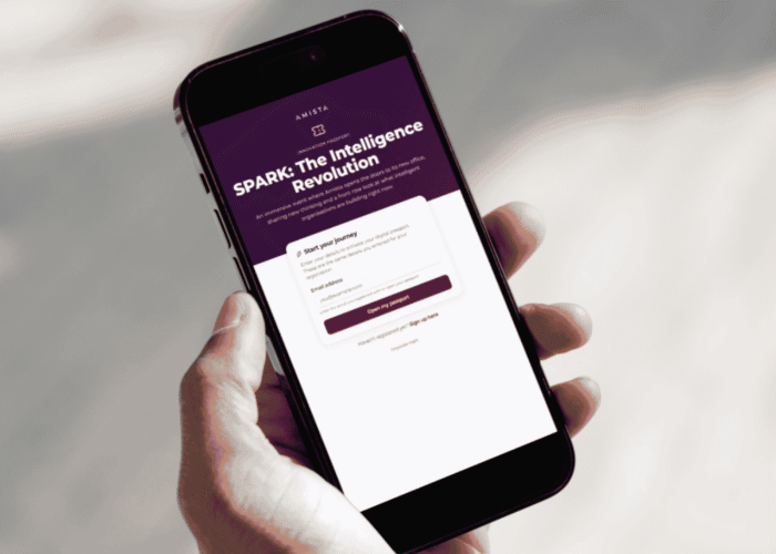 A hand holds a smartphone displaying a website titled "SPARK: The Intelligence Revolution" with a signup form.